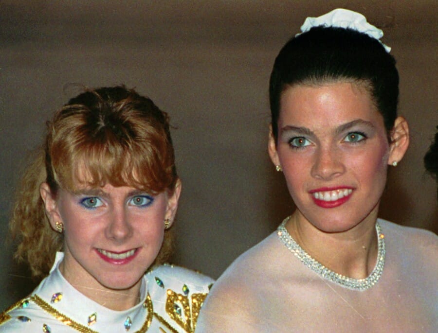 Tonya Harding standing to the left of Nancy Kerrigan. They’re both smiling. 